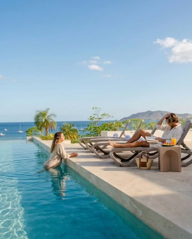 Guests relaxing poolside at Naia, Tamarindo Bay in the background